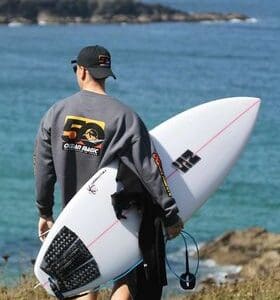 surfer walking to Newquay beach with ns surfboard